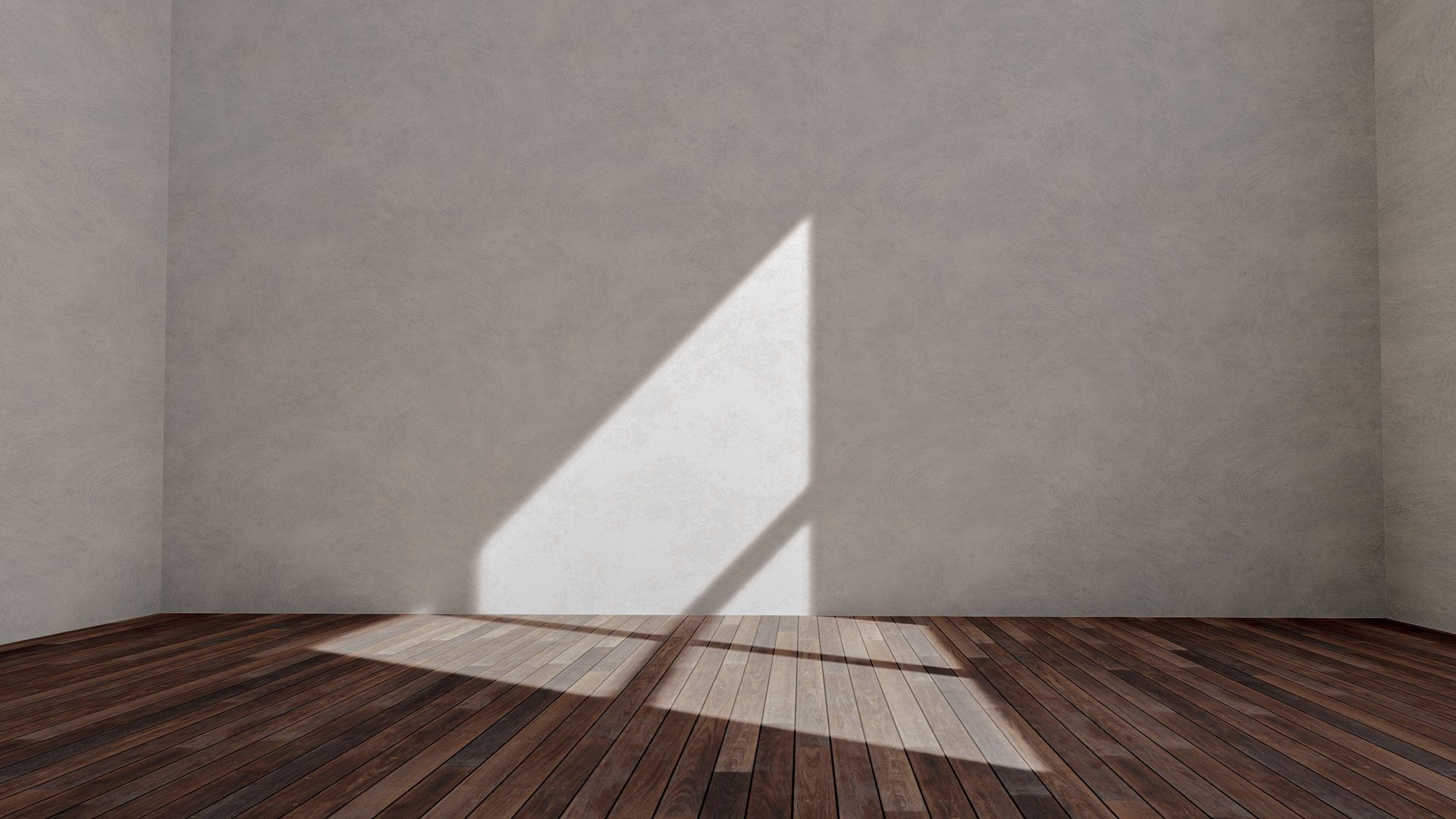An empty room with a wooden floor and daylight falling across a bare wall